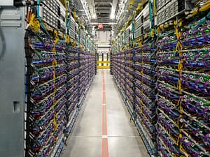 Pasillo de un centro de datos de Google con hileras de servidores, cables y equipos para procesamiento informático