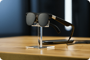 Gafas de realidad extendida XREAL Aura negras con lentes oscuros sobre un soporte y cable de conexión