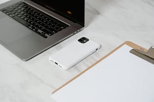 Computador portátil, teléfono y documentos sobre un escritorio, fotografía referencial de productividad